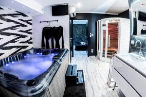 a bathroom with a tub and a sink at Appart Hotel GLAM88 Suites avec SPA et Sauna Privatif in Remiremont