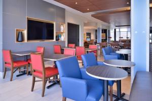 un restaurante con mesas y sillas y TV de pantalla plana en Holiday Inn Express & Suites - Olathe West, an IHG Hotel, en Olathe