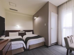 山形市にあるアパホテル 山形駅前大通 のベッド2台、デスク、窓が備わるホテルルームです。