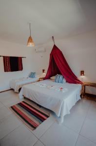 een slaapkamer met 2 bedden en een rode klamboe bij Villa Aurora in Flecheiras