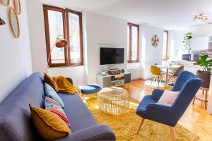 uma sala de estar com um sofá azul e cadeiras em Duplex lumineux 2 chambres centre zone piétonne em Valence