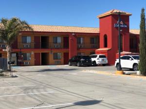a hotel with cars parked in front of a parking lot at California Inn Hotel and Suites Adelanto US 395 in Adelanto