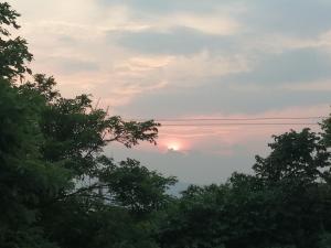 una puesta de sol en el cielo con árboles en primer plano en Casa Campestre Rivera, en Rivera