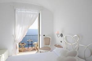 a white bedroom with a view of the ocean at La Maurella in Praiano