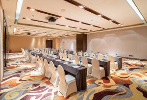 Crowne Plaza Wuxi Taihu, an IHG Hotel في ووشي: قاعة اجتماعات مع طاولات طويلة وكراسي بيضاء