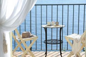 a balcony with two chairs and a table with cups on it at La Maurella in Praiano