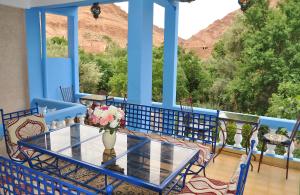 un porche azul con una mesa con flores. en A Secret Garden, en Tinerhir