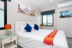 a bedroom with a large white bed with blue pillows at The Title Residencies Naiyang Beach in Nai Yang Beach