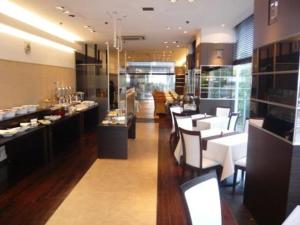a restaurant with white chairs and tables and a buffet at Hiroshima Intelligent Hotel Annex in Hiroshima