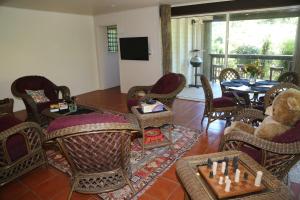 sala de estar con sillas de mimbre y mesa con tablero de ajedrez en Licuala Lodge, en Mission Beach