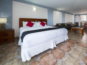 a bedroom with a large white bed and a couch at Suites de Reyes in Irapuato