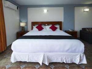 a bedroom with a large white bed with red pillows at Suites de Reyes in Irapuato