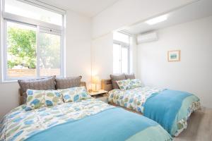 a bedroom with two beds and a window at stylish House URUMA in Uruma