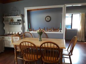 a dining room table with chairs and a vase of flowers at Lady Bowen Bed & Breakfast in Thames