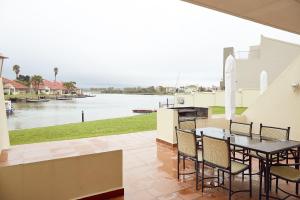 un patio con mesa y sillas y vistas al río en First Group Port Owen Marina, en Velddrif