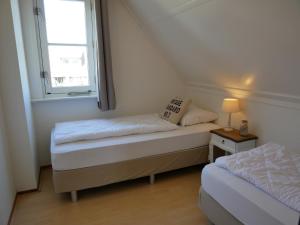 een kleine kamer met twee bedden en een raam bij Villa Buiten 58 in Callantsoog