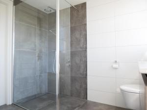 een douche met een glazen deur in een badkamer bij Villa Buiten 58 in Callantsoog
