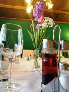 una mesa con copas de vino y un jarrón de flores en Rooms Baranjska Oaza, en Bilje