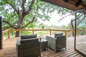 two chairs and a table on a deck with a tree at Elephant Plains Game Lodge in Sabi Sand Game Reserve