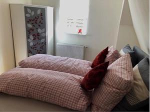 a bed with red pillows on top of it at Wohlfühl Appartments in Felsberg
