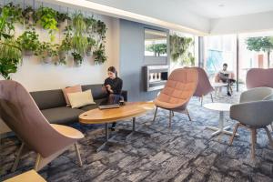 a woman sitting on a couch in a waiting room at Novotel Lausanne Bussigny in Lausanne