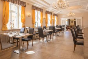 a restaurant with tables and chairs and a chandelier at Hotel Unter den Linden in Krems an der Donau