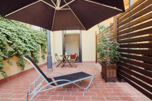 un banco con sombrilla en un patio de ladrillo en Hostal Live Barcelona, en Barcelona