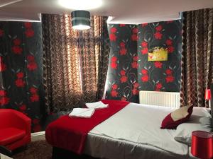 a bedroom with a bed and a red chair at Pacific Inn London Heathrow in Southall