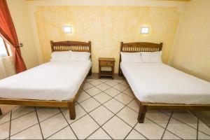 2 camas individuais num quarto com piso em azulejo em OYO Hotel La Glorieta ,Huichapan ,Balneario Camino Real em Huichapan