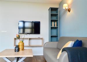 ein Wohnzimmer mit einem Sofa und einem TV an der Wand in der Unterkunft Vlugtenburg in s-Gravenzande