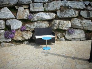 a chair and a table in front of a stone wall at Gästehaus MAXLTONI in Kitzeck im Sausal