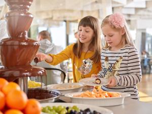 two girls are preparing food at a buffet at Maistra Select Family Hotel Amarin in Rovinj