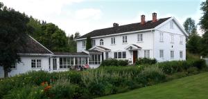 a white house with a garden in front of it at Sanner Hotell in Gran