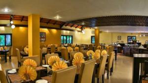 a dining room with tables and chairs in a restaurant at Kadkani River Resort in Siddapur