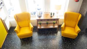 two yellow chairs and a table in a room at Hotel Josein in Comillas