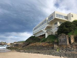 a white building on a cliff next to the ocean at Hotel Josein in Comillas