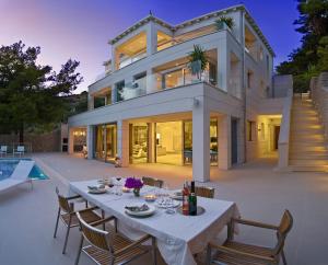 a dining table in front of a house at Luxury Seafront Villa My Dream with private pool, jacuzzi and staff at the beach on Brac island - Sumartin in Selca