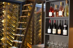 a shelf full of wine bottles and wine glasses at Les Chambres de l'Oustalet in Gigondas