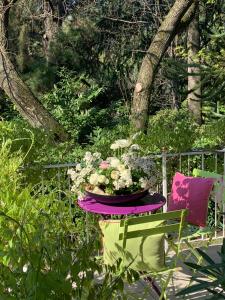 een tafel met een pot bloemen en een stoel bij Hotel Zima in Merano