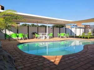 a small swimming pool with green chairs and a table at Seagull Lodge in Richards Bay