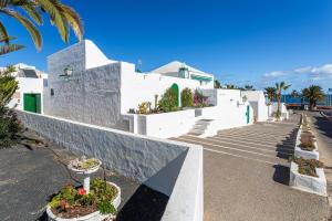 Un edificio blanco con escaleras y flores en macetas. en The Beach House - Central location - Private Plunge Pool - Roof Terrace - 100m to Beach, en Costa Teguise