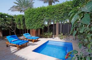 una piscina con 2 sillas azules y una piscina en Anantara Desert Islands Resort & Spa en Da‘sah