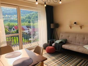 a living room with a couch and a large window at Olympic Residence in Szczyrk