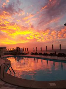 een zwembad met een zonsondergang op de achtergrond bij XQ El Palacete in Morro del Jable