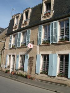 un edificio con persianas azules y flores en las ventanas en Chambre d'hôtes - Dodo et tartines, en Bayeux