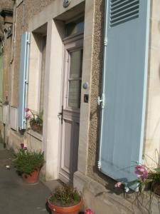 a door on the side of a building with potted plants at Chambre d'hôtes - Dodo et tartines in Bayeux