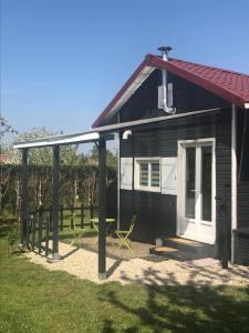 une maison noire avec une terrasse couverte et une table de pique-nique dans l'établissement Petit Chalet Chez Marcelline, à Amécourt