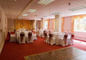 een feestzaal met tafels en stoelen met witte tafelkleden bij King Charles Hotel in Gillingham