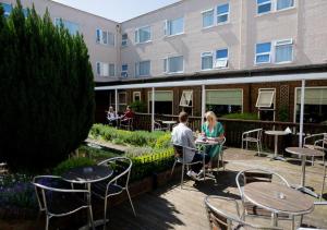 duas pessoas sentadas em mesas fora de um edifício em King Charles Hotel em Gillingham