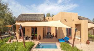 une maison avec une piscine en face de celle-ci dans l'établissement Anantara Sir Bani Yas Island Al Sahel Villas, à Da‘sah